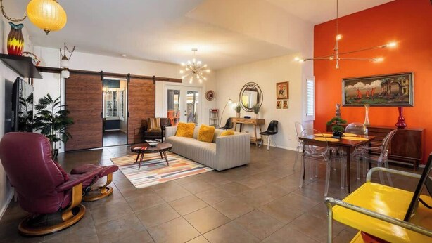 Een moderne woonkamer met een bank, stoelen, een eettafel en een keukenhoek.