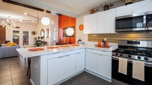 Een moderne keuken met witte kastjes, een roestvrijstalen fornuis en een magnetron.