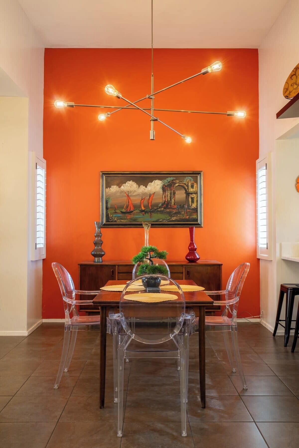 Un coin repas comprenant une table, des chaises, un lustre et un tableau au mur.