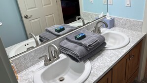 Une salle de bain avec deux lavabos, un miroir et un porte-serviettes.