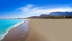 A beach with clear turquoise water, a sandy shore, and buildings in the background. - El Forti, 2 bedrooms, center, by Bookindenia (Dénia)