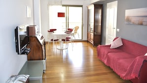 A living room with a red sofa, a dining table with chairs, a television, and a cabinet. - El Forti, 2 bedrooms, center, by Bookindenia (Dénia)