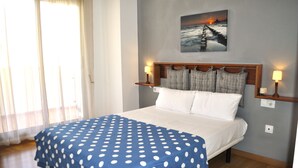 A bedroom with a bed, a painting of a sunset over the ocean, and two bedside lamps. - El Forti, 2 bedrooms, center, by Bookindenia (Dénia)