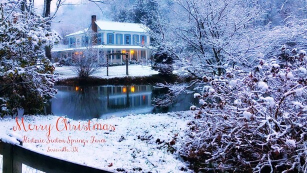 Ein historischer Seaton Springs Farm mit einem großen Haus und einem Teich, umgeben von schneebedeckten Bäumen.
