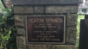 Un mur de pierre sur lequel est fixée une plaque portant l’inscription suivante : « SEATON SPRINGS, CONSTRUIT EN 1884, RESTAURÉ DE 1975 À 1976 PAR GARFIELD QUILLIAMS ET FILS, JACK ET JOHN GRACE ET RAY PORTER ».