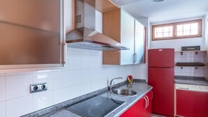 A modern kitchen with white cabinets, a red refrigerator, a stainless steel sink, and a built-in stove. - Housing León- The Galery (León)