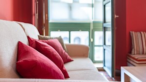 A sofa with red cushions in a room with red walls and a green door. - Housing León- The Galery (León)