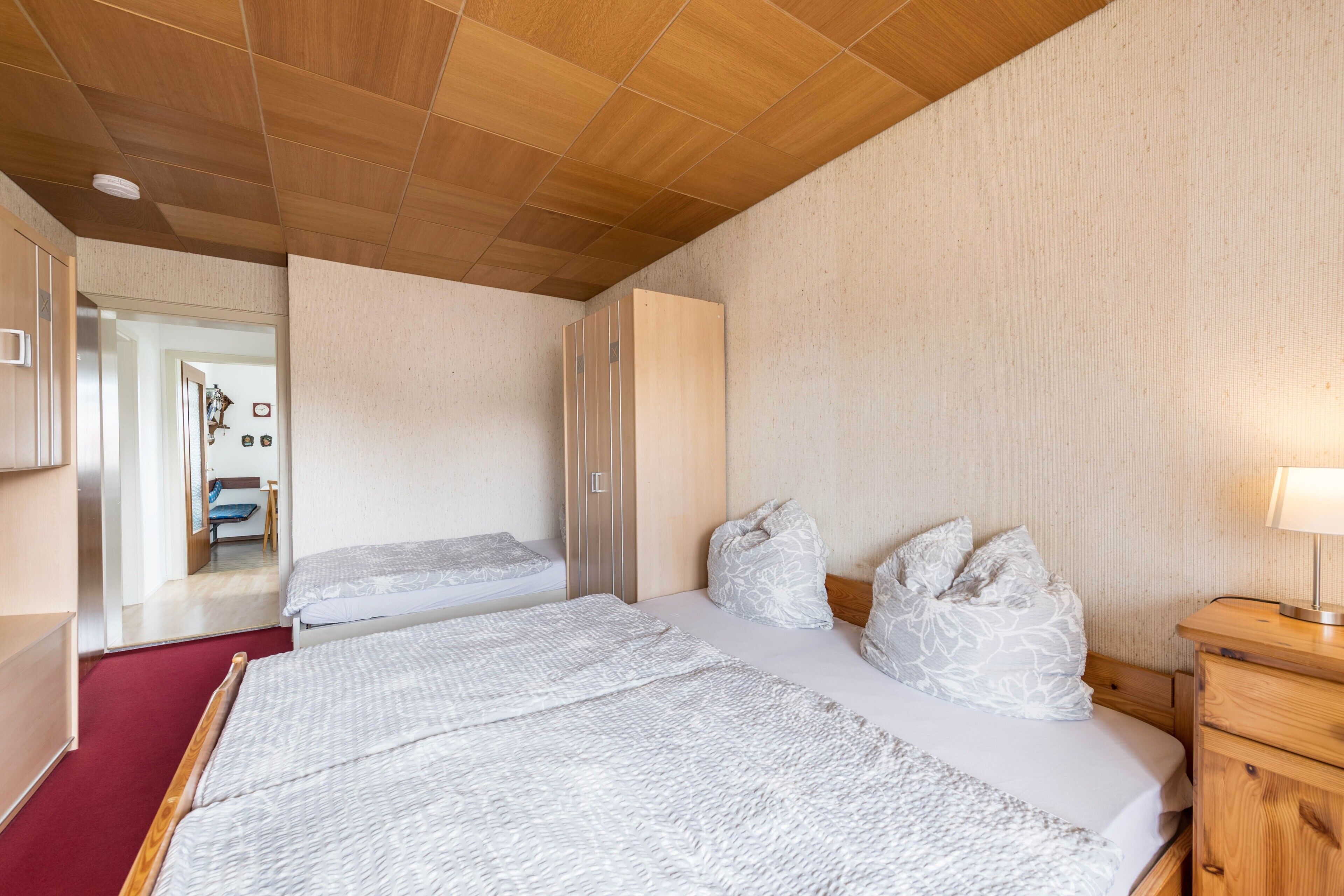 Ein Schlafzimmer mit zwei Betten, Holzboden und einem Nachttisch mit Lampe.