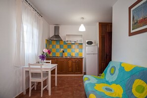 A compact kitchen with a microwave, a stove, and a patterned backsplash.