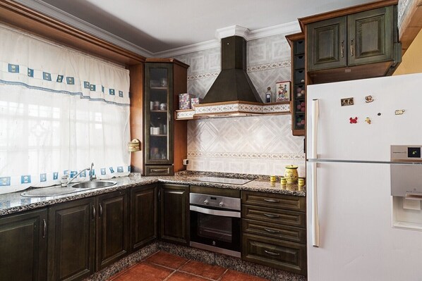 Una cocina con armarios de madera oscura, un refrigerador blanco, una estufa y un microondas.