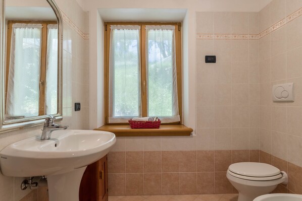 Un baño con lavamanos, ventana y retrete.