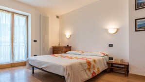 Ein Schlafzimmer mit einem Bett, Holzboden, einem Nachttisch, einer Kommode und einem Fenster mit Vorhängen.