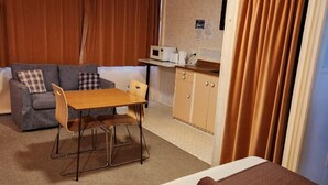 Une chambre d’hôtel comprenant un lit, une table à manger avec des chaises, un coin cuisine et un canapé.