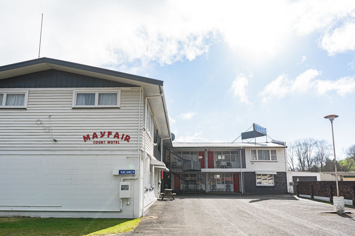 A motel with a sign reading "MAYFAIR COURT MOTEL" and a "VACANCY" sign.