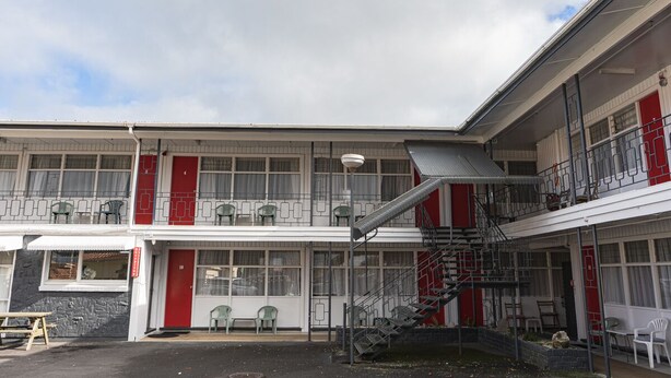Un immeuble de deux étages, doté d’une façade rouge et blanche, de nombreux balcons et d’un escalier menant à l’étage supérieur.