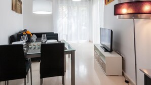 Un soggiorno moderno con zona pranzo, dotato di televisore, lampada e divano.