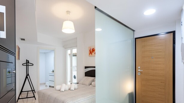 Una camera da letto moderna con un letto, una porta in legno e un divisorio in vetro.