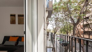 Un balcone con vista su una strada alberata e auto parcheggiate.