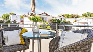 A balcony with wicker chairs, a glass table, and a white vase with flowers. - Ferienwohnung 2 mit Meerblick und Südbalkon (Heringsdorf)