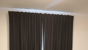 Een kamer met een bed, een klein tafeltje en een gordijn.