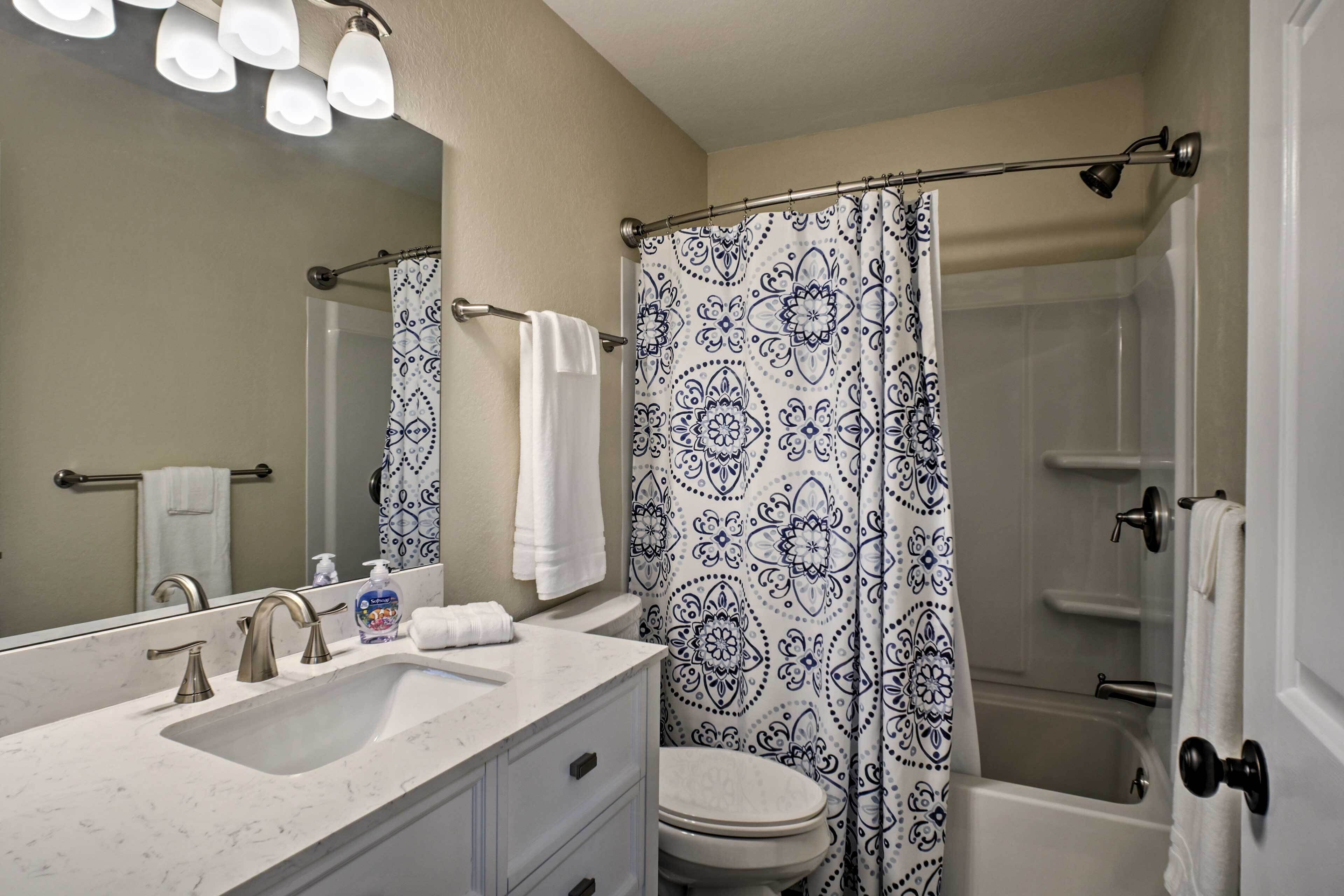 A bathroom with a sink, mirror, toilet, and shower curtain.
