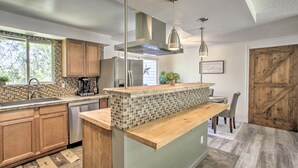 A modern kitchen with wooden cabinets, a tiled backsplash, stainless steel appliances, and pendant lighting. - The Overlook Gem: Stunning Views & Serenity Awaits (Nine Mile Falls)