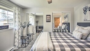 A bedroom with a checkered bedspread, a ceiling fan, and a view of a dining area. - The Overlook Gem: Stunning Views & Serenity Awaits (Nine Mile Falls)