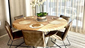 A round dining table with a woven centerpiece, surrounded by leather chairs. - A truly exceptional villa (Xàbia)
