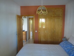 Cozy retreat with a large bed, wardrobe, and hanging light fixture.