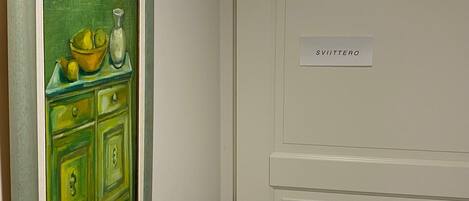Una puerta con un letrero que dice "SVITTERO" y un cuadro de un armario verde con un tazón y limones.