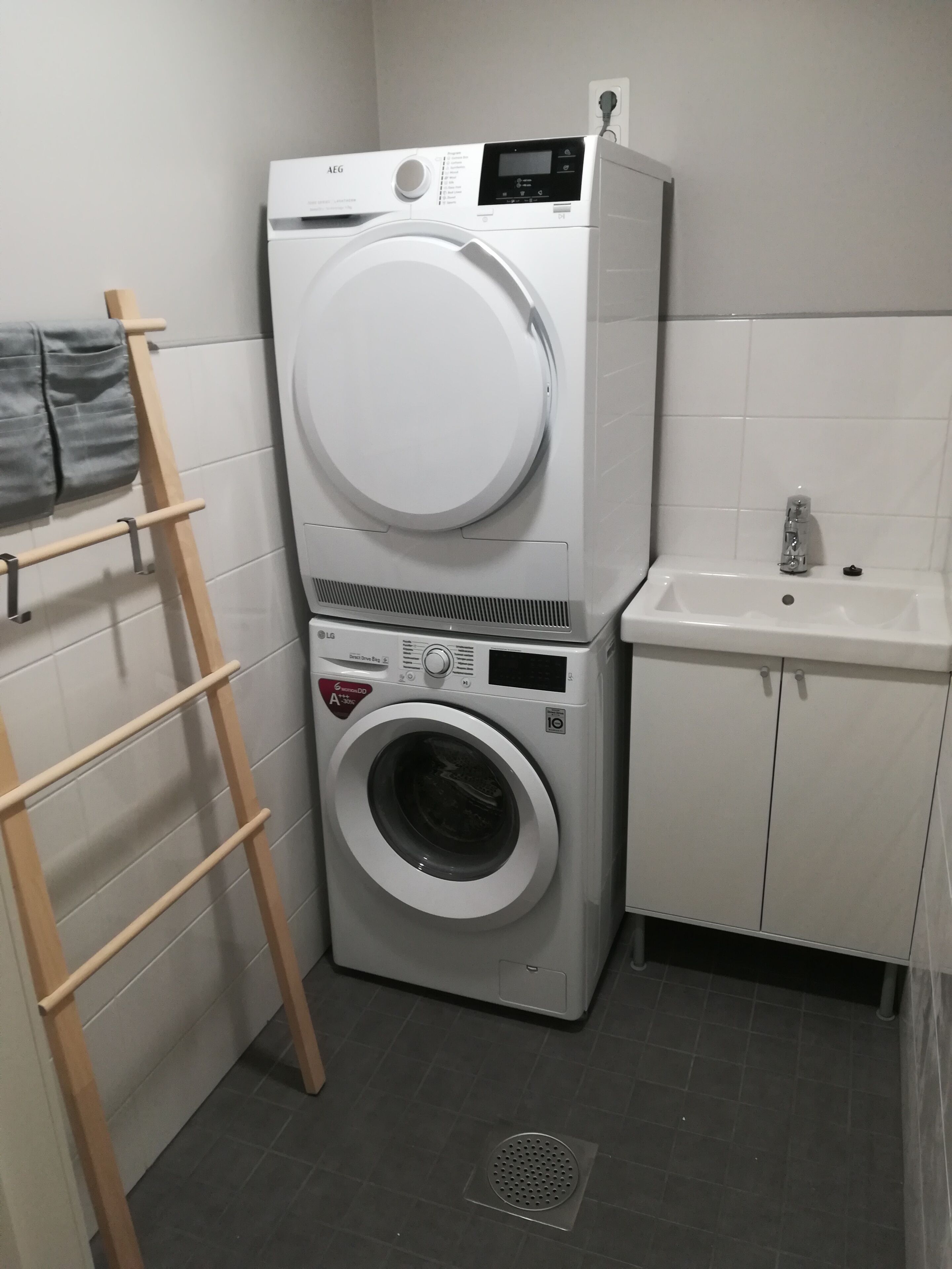 A laundry area with stacked washing machines and a sink.