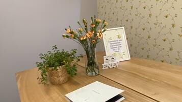 Ett träbord med ett vitt anteckningsblock, en vas med blommor och en inramad skylt.