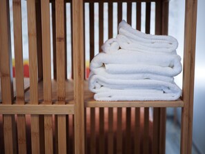A stack of white towels on a wooden shelf.
