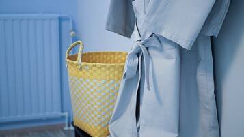Un baño con una bañera blanca, una cesta amarilla de cuadros y una pared azul.