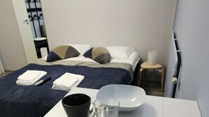 A neatly arranged hotel room with a bed, bedside table, and a small stool. - Savonlinna Rentals (Savonlinna)
