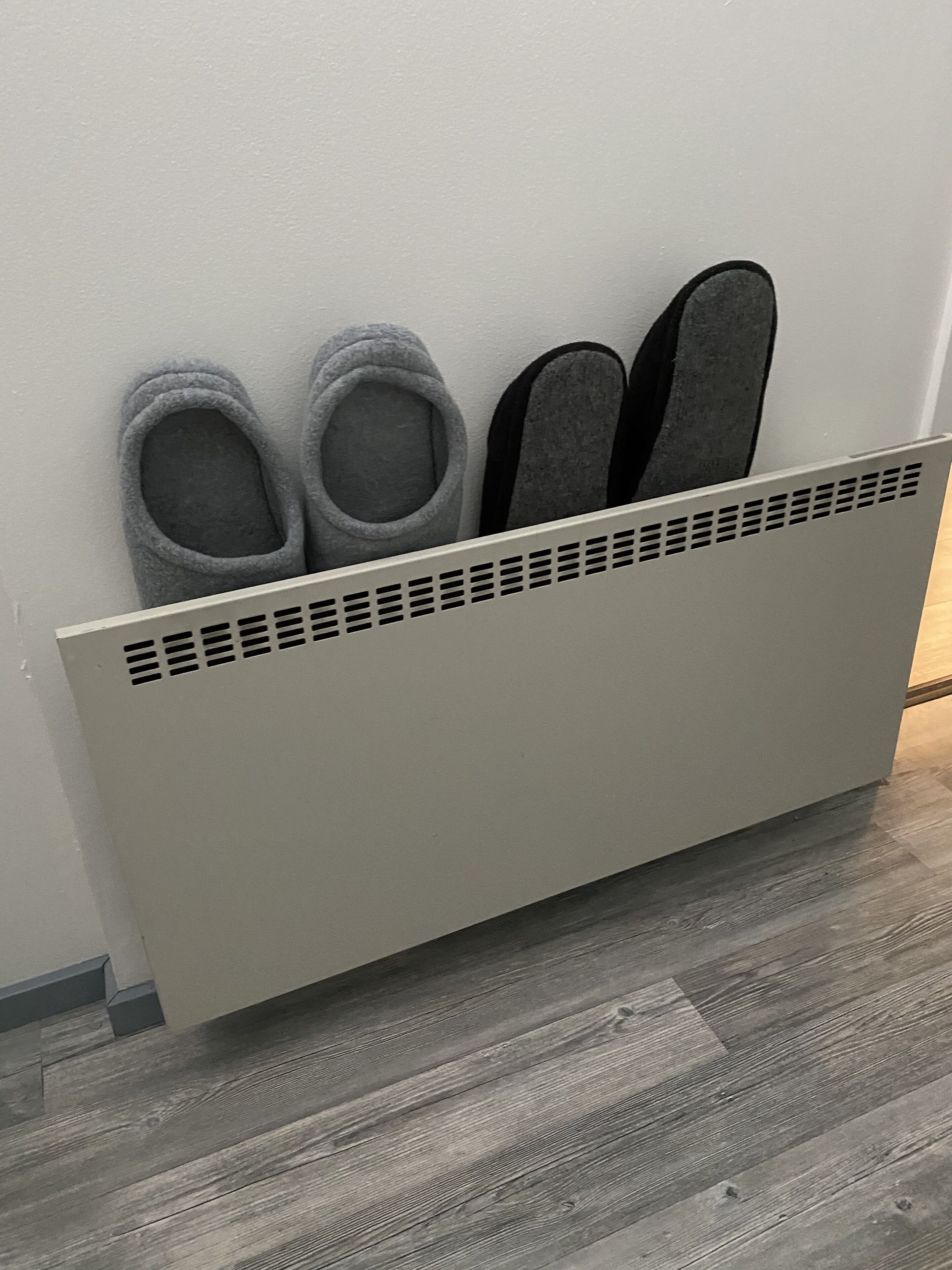 A wall-mounted shoe rack with two pairs of slippers and a pair of sandals.