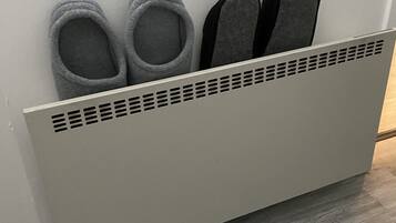 A wall-mounted shoe rack with two pairs of slippers and a pair of sandals.