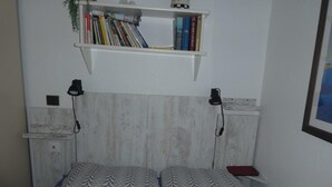 Ett sovrum med en säng, en hylla med böcker och en vägglampa.