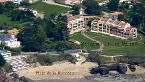 Ett flygbildsbild av ett bostadsområde med en stor byggnad som är märkt med texten ”Résidence Claire Marine” och en strand som heter ”Plage de La Birochère” i förgrunden.