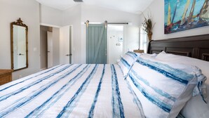 A bedroom with a bed, a mirror, a door, and a painting on the wall. - Best Family Vacation at the Beach or the Pool. (Tarpon Springs)