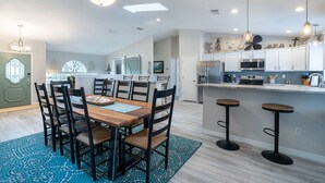 A modern kitchen with white cabinets, stainless steel appliances, and a bar area with stools. - Best Family Vacation at the Beach or the Pool. (Tarpon Springs)