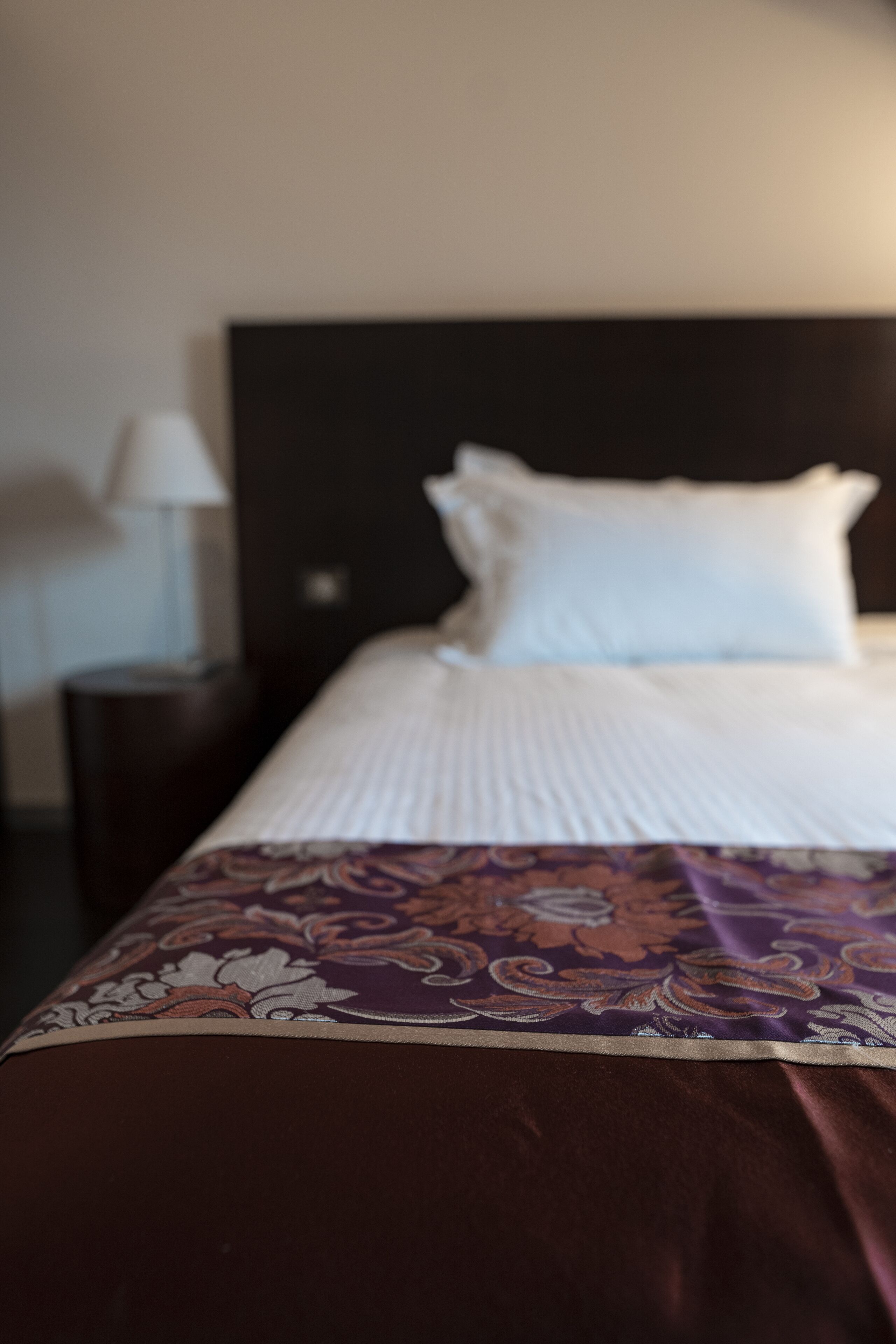 Un lit avec une couvre-lit à motifs et des oreillers blancs.