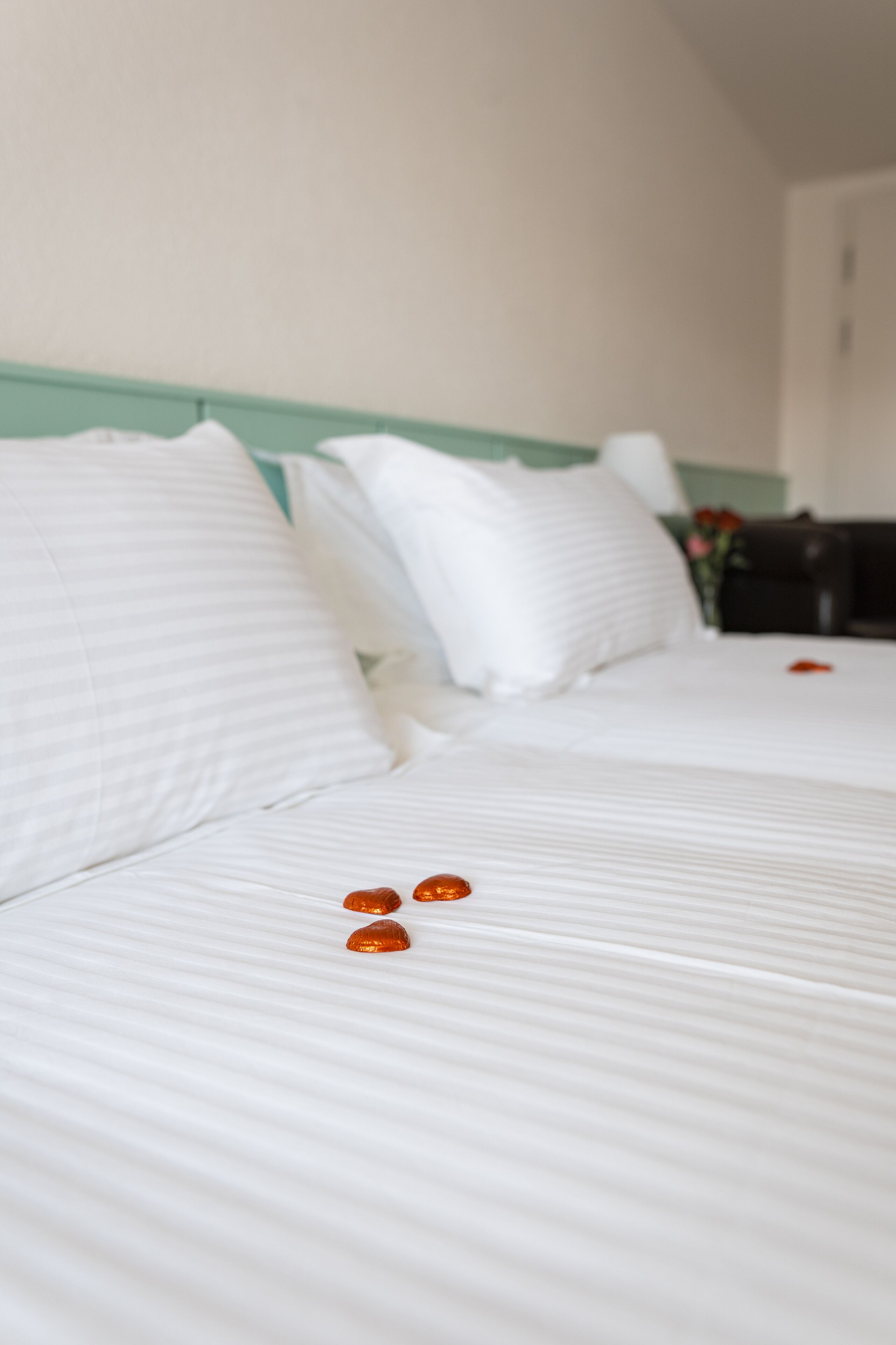 Ein Hotelzimmer mit zwei Betten, weißen Leinentextilien und einem grünen Kopfteil.