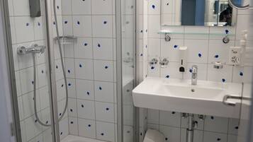 A modern bathroom with a glass-enclosed shower, a white sink, and a mirror above it.