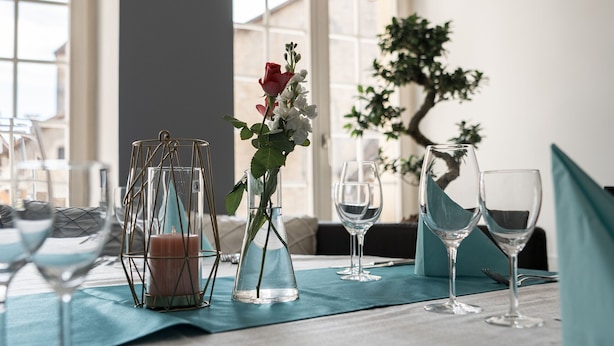 A dining table set with glassware, a candle, and a vase with flowers. - Swiss Hotel La Couronne (Avenches)