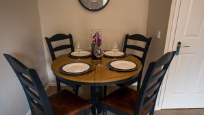 Mesa de comedor para cuatro personas, con un jarrón de flores moradas en el centro.