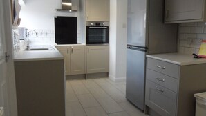 A kitchen with a stainless steel refrigerator, a built-in oven, and a sink. - 3 Bed Broomfield Road Newport Shropshire (Newport)