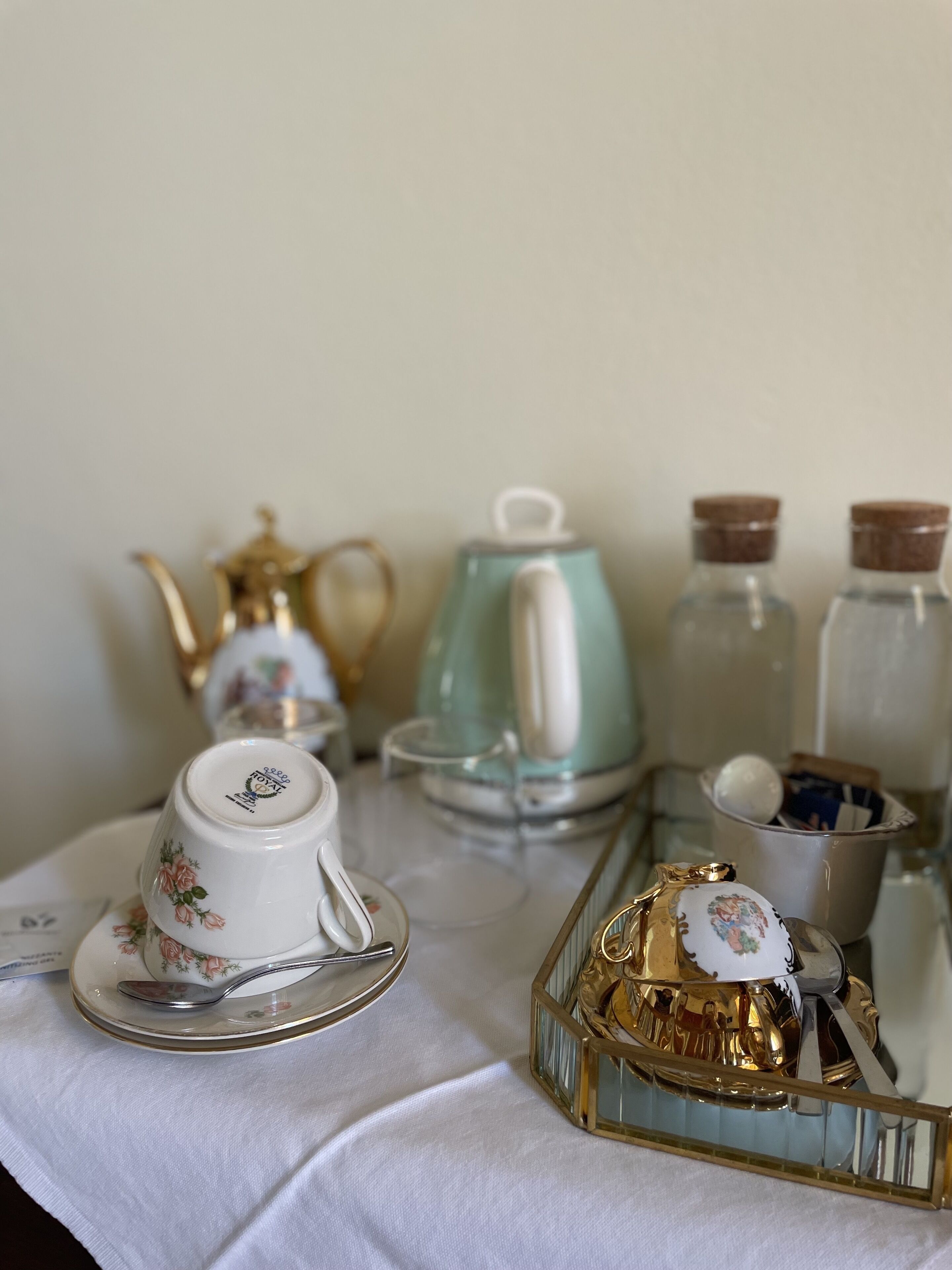 A table set with a tea set, including a teapot, cups, and saucer, and a decorative gold box.