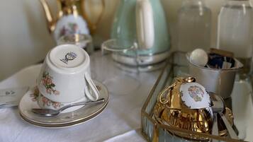 A table set with a tea set, including a teapot, cups, and saucer, and a decorative gold box.