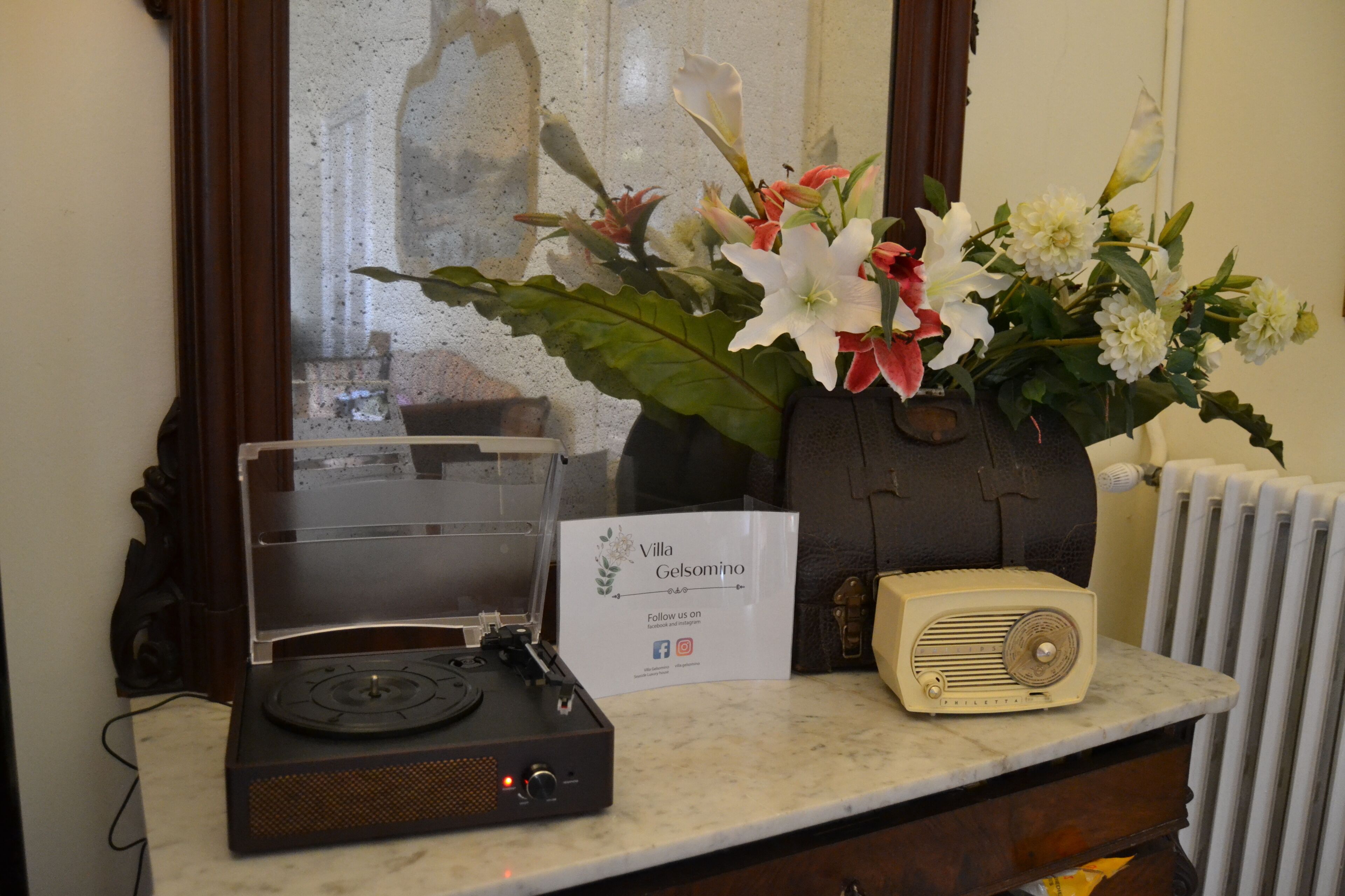 A vintage radio, a record player, and a floral arrangement on a marble countertop.
